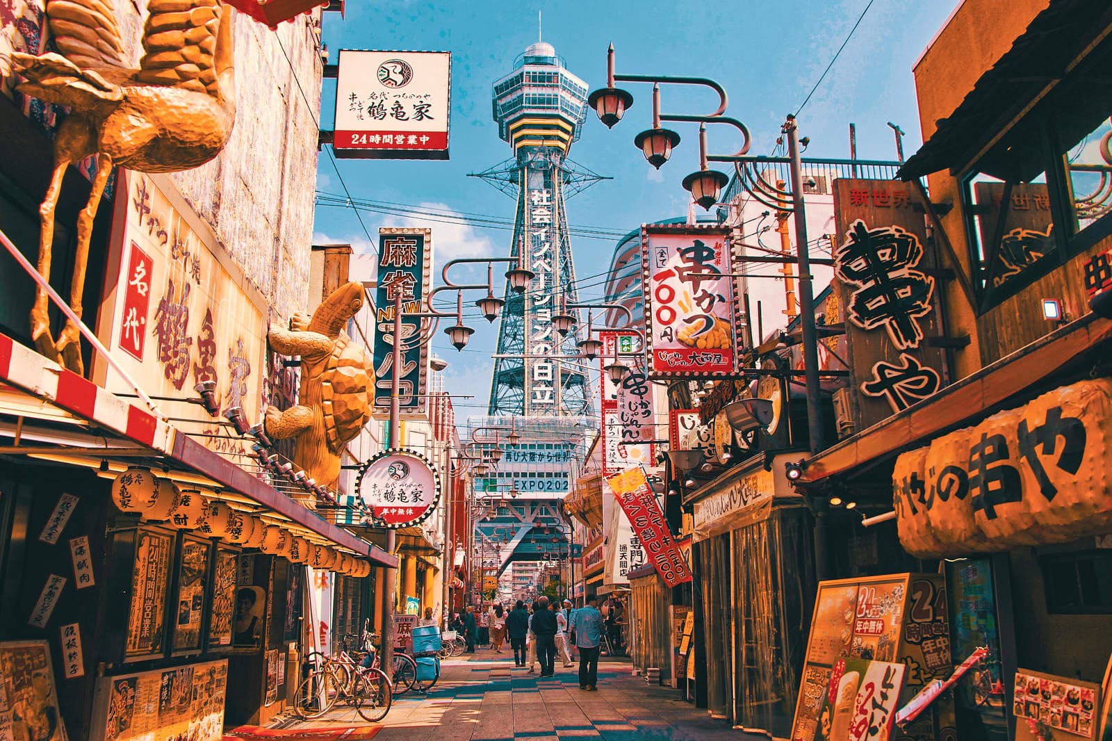Skyline von Osaka mit erhöhten Bahntrassen, dicht bebauten Straßen und Neonlichtern bei Dämmerung
